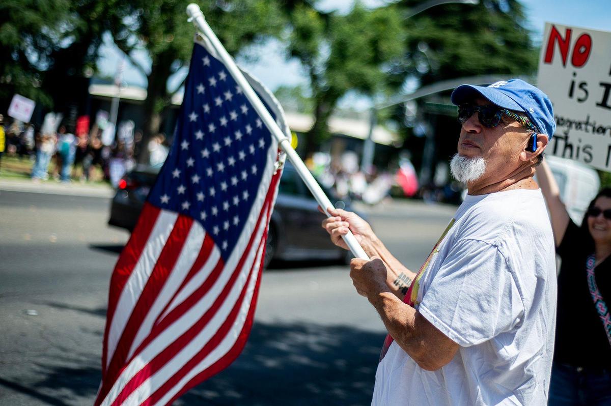 Daniel Torres, 67, of Merced, waves an American flag as he takes part in a “No Kings” protest in Merced, Calif., on Saturday, June 14, 2025. “It’s about American values, what America is all about,” said Torres. “Right now we seem not to have the same values as treating everyone the same. Torres said immigrants built this country and he feels they are being treated poorly. “So this is us, this is uniting–this is beautiful,” he said.