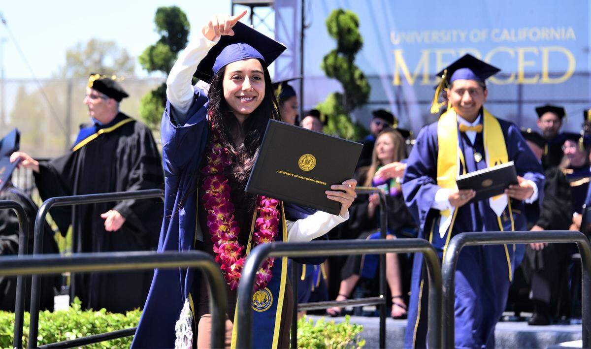UC Merced graduate Darlyn Ayala points to friends and family as she makes her way off the stage during the 2022 UC Merced Graduation Ceremony on Saturday, May 14, 2022 at UC Merced in Merced, Calif. 