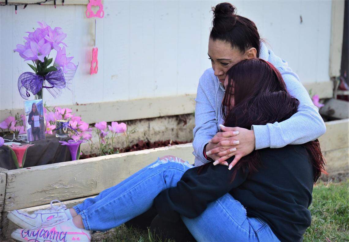 Victoria Lopez of Los Banos hugs her daughter Yesenia Jaurigue in front of a flower bed they decorated in honor of Lopez’s daughter Tatyanna Lopez, who was killed one year ago in Merced.