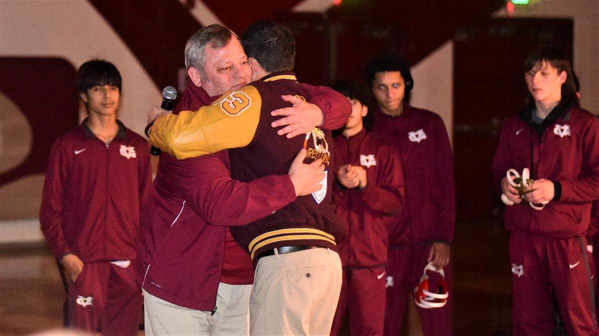 Golden Valley High assistant coach Andrew Powers (right) hugs Cougars wrestling coach Chopper Mello during a ceremony honoring Mello for collecting his 400th career win this season on Tuesday, Jan. 17, 2023 at Golden Valley High School.