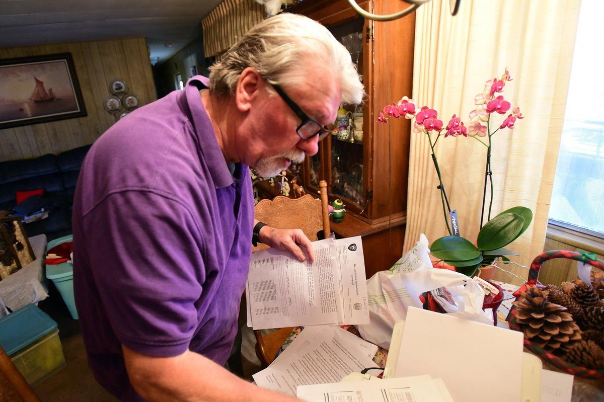 Charlie Strother looks over the bills, police reports and an eviction notice on Wednesday, Dec. 12, 2018, he said are related a case of fraud at the Sierra Portal mobile home park in Merced.