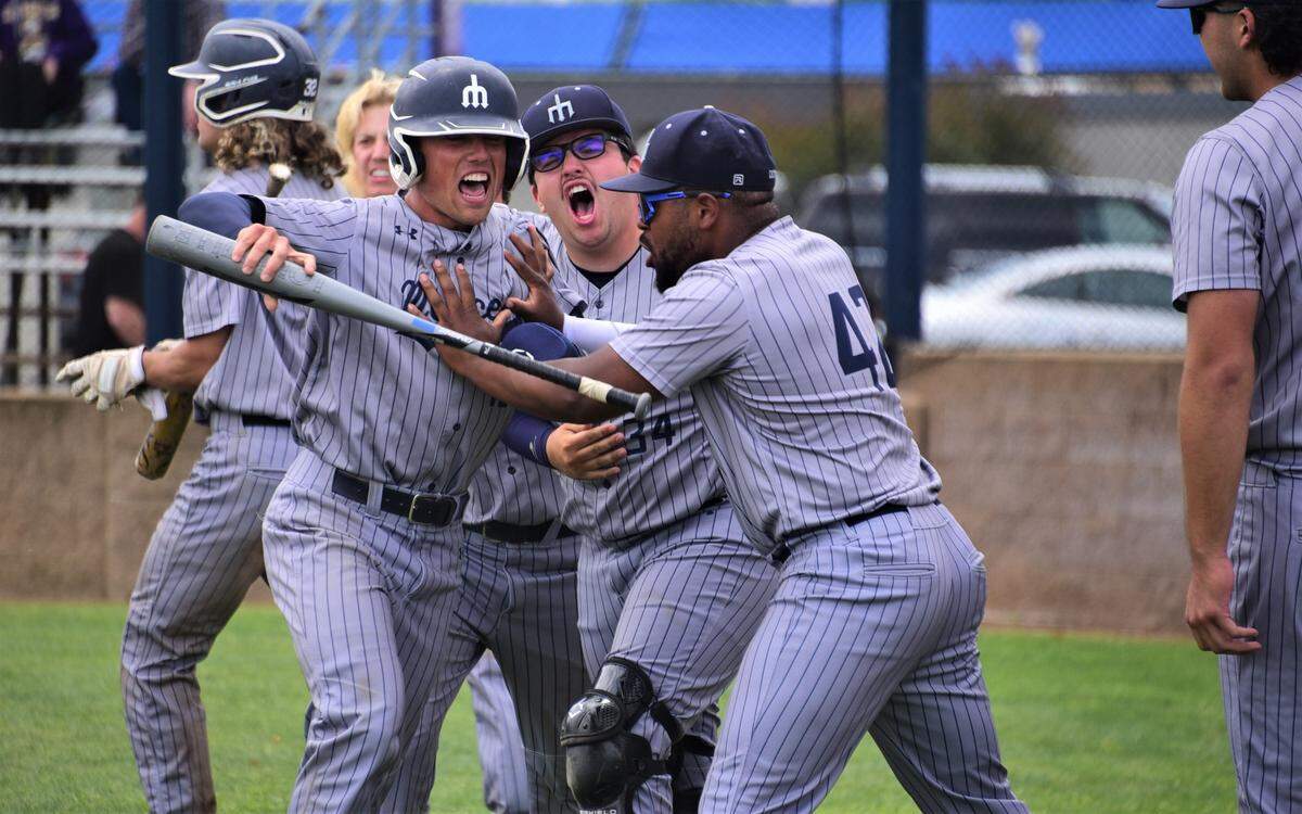 Merced College’s Nate Silva (center) is greeted by teammates after scoring the tying run in the ninth inning in a playoff game against Canada College on Saturday, May 6, 2023.