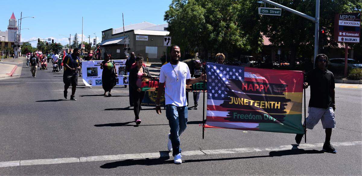 Lonnie Pierce, left, and his father Roscoe Pierce hold a Happy Juneteenth flag as they lead the first Juneteenth Parade down Martin Luther King Jr. Way in Merced, Calif. on Saturday, June 18, 2022.