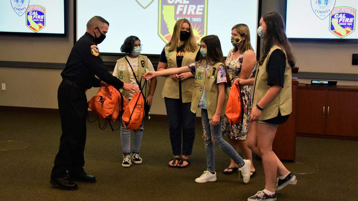 Merced County Fire Department Assistant Chief Mark Pimentel hands out a certificate to Girl Scout troop member Violette Walker after her troop donated six pet oxygen masks to the Merced County Fire Department on Wednesday, June 2, 2021 in Atwater, Calif.