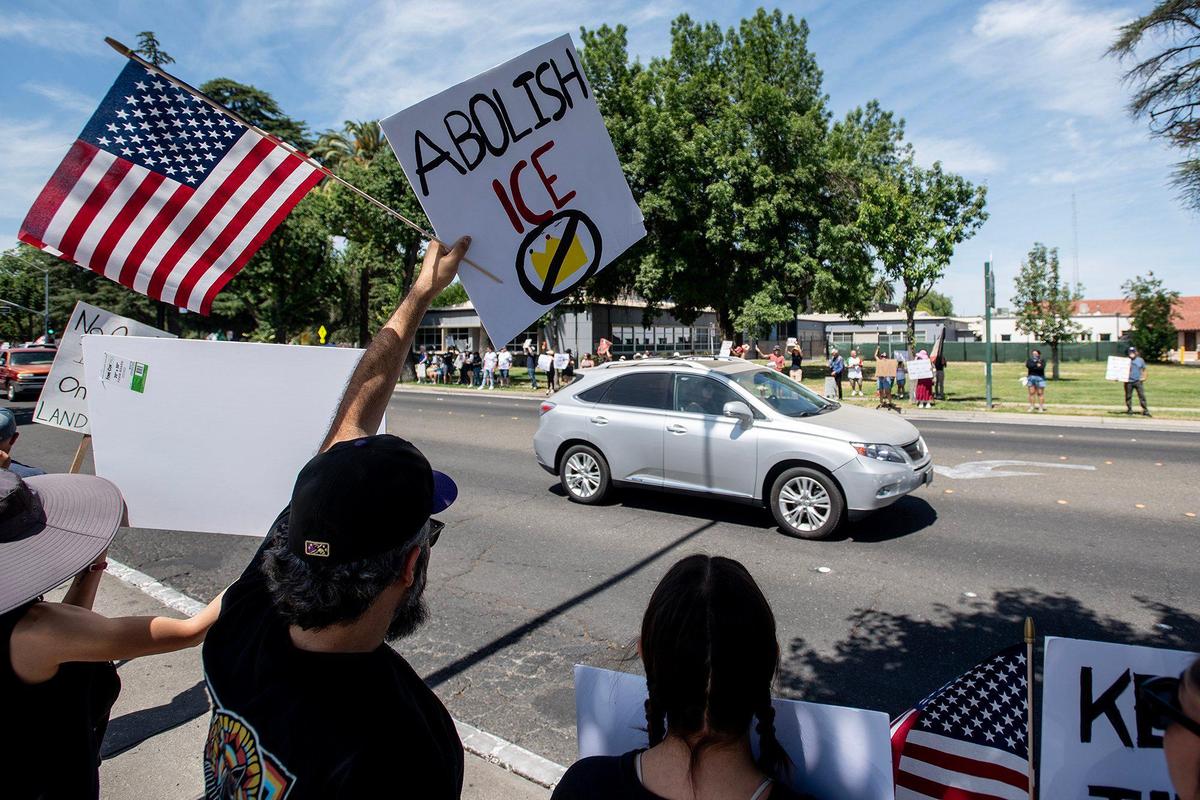 Protesters hold signs and wave flags along M Street as they take part in a “No Kings” protest in Merced, Calif., on Saturday, June 14, 2025.