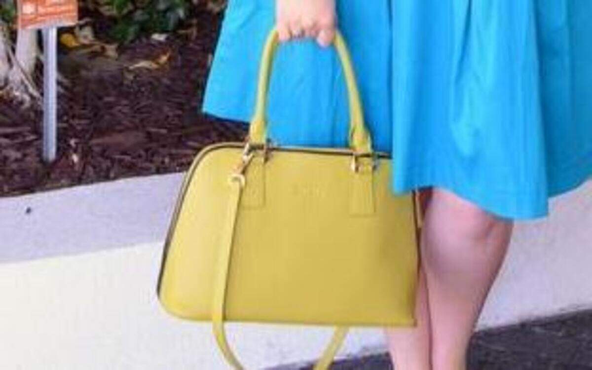 Fashion blogger Michelle Oliver pairs a midi skirt with a yellow bag.