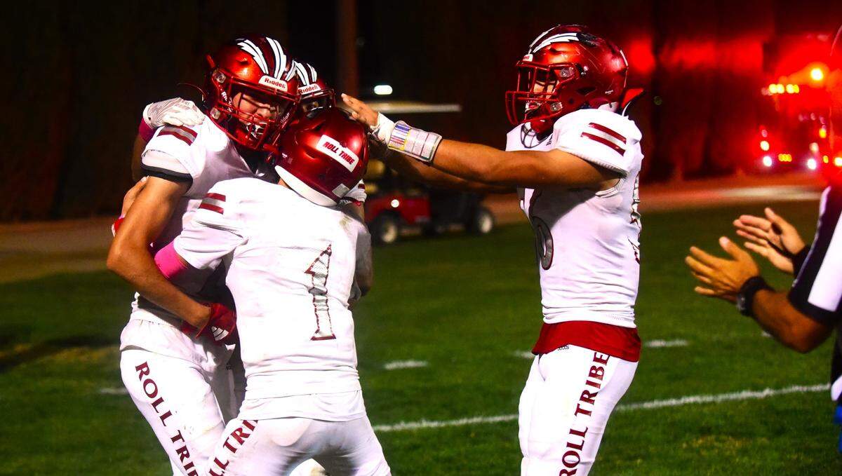 Chowchilla High School quarterback Davian Stephenson (1) hugs receiver Anthony Avila (left) after Avila catches a touchdown in the third quarter during a game against Caruthers on Friday, Oct. 20, 2023.