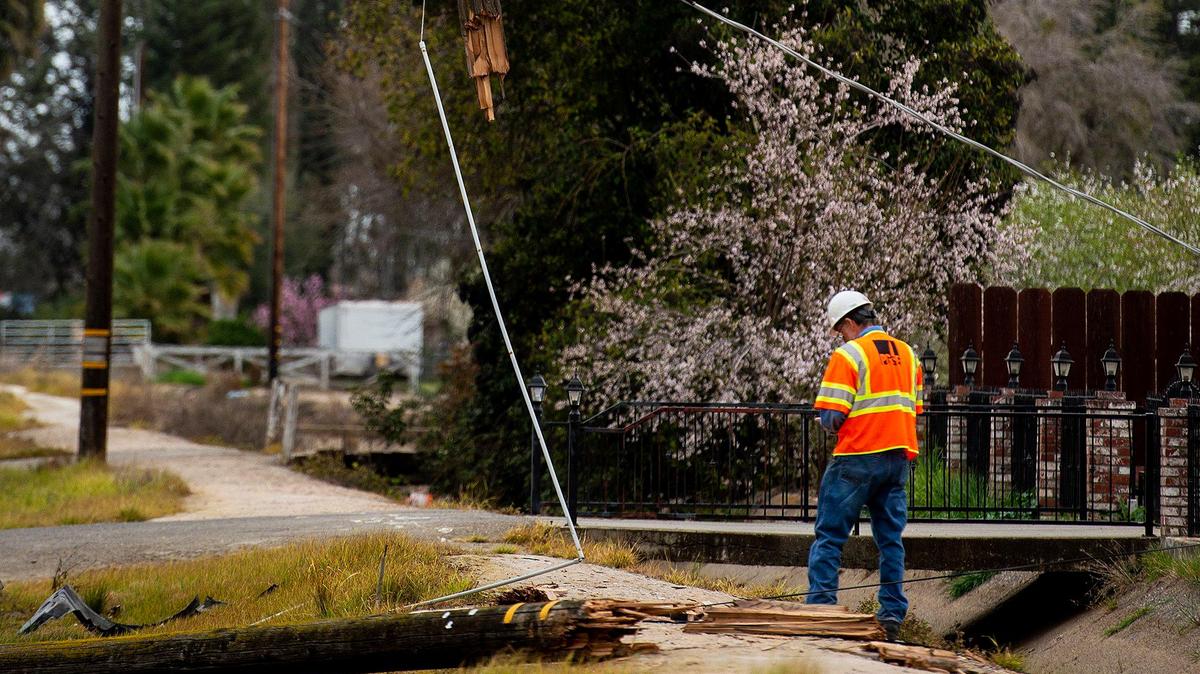 Merced police officers and firefighters respond to the scene of a solo-vehicle crash that severed a power pole and left a vehicle in a canal along East Childs Avenue in Merced, Calif., on Sunday, March 1, 2020. According to Merced Fire Battalion Chief Mickey Brunelli, the road is closed in the area as Pacific Gas and Electric Company work to restore power and remove power lines from the roadway.
