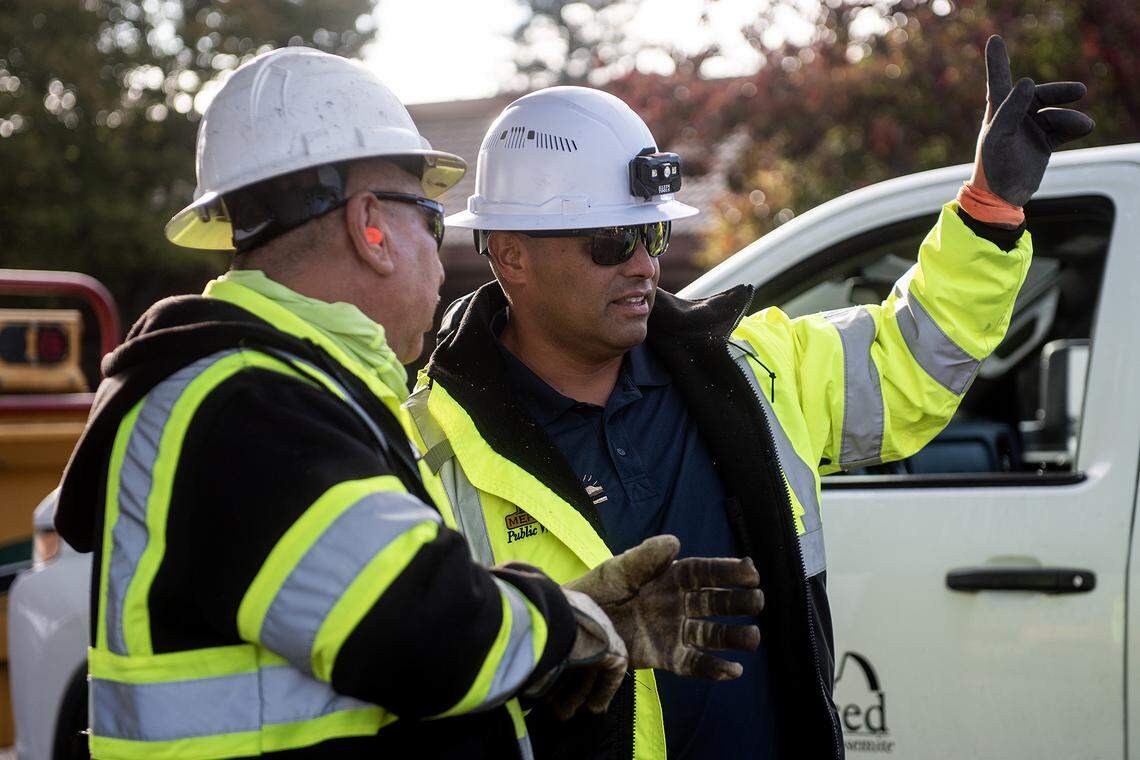City of Merced Arborist and Public Works Director for Parks and Trees Division, Angel Nunez, 46, right, speaks with City of Merced employee and crew member Valente Torres, left, as crews work to remove selected trees in the median along West Olive Avenue in Merced, Calif., on Thursday, Nov. 6, 2025. 