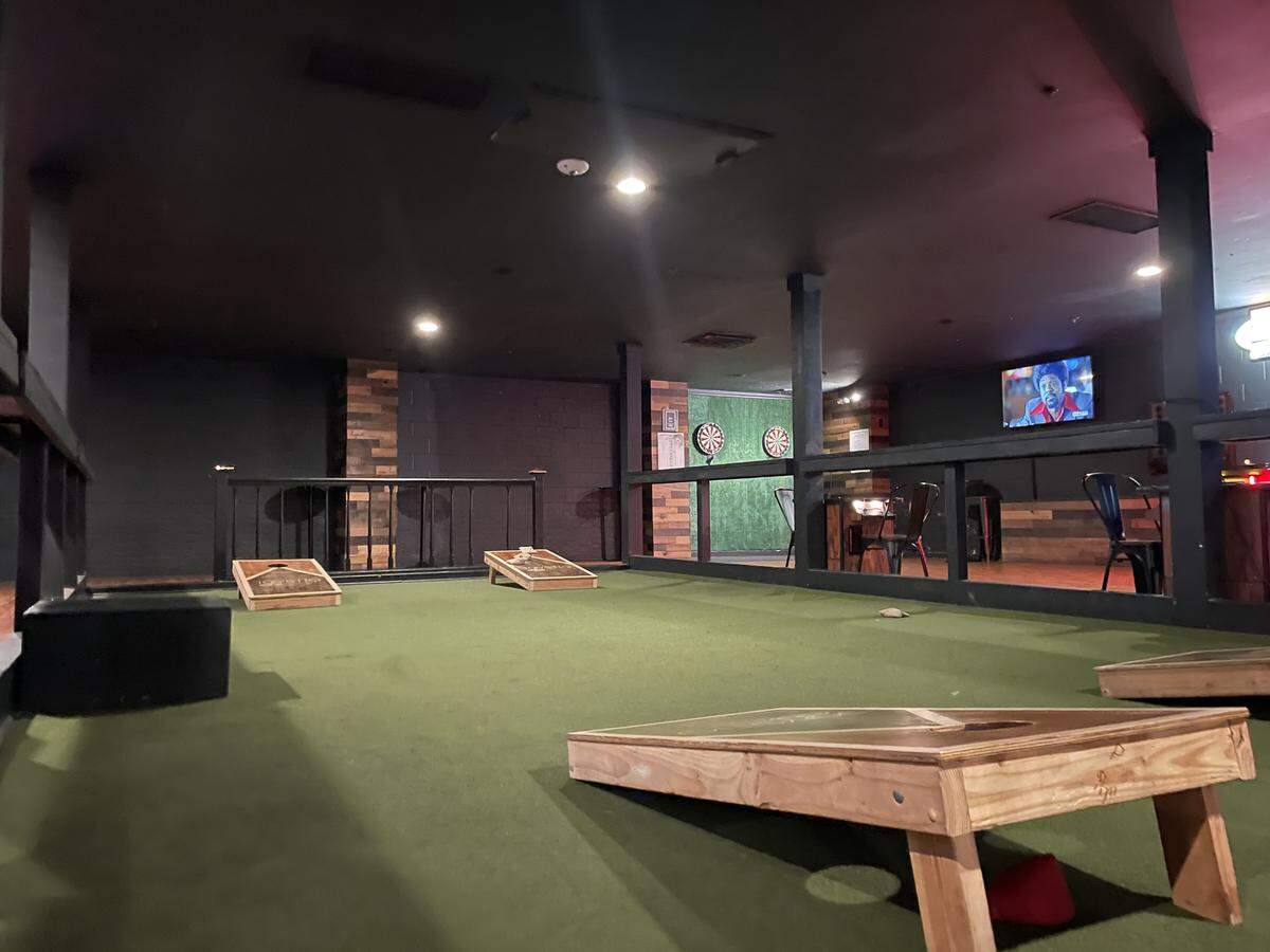 Four cornhole boards on a small indoor court.