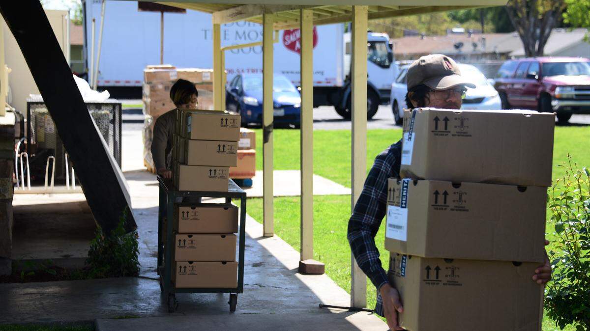 Volunteers Etuale Muliaga-Lopez (front) and R.J. Lopez help carry boxes of food at the Salvation Army on Friday afternoon in Merced County.