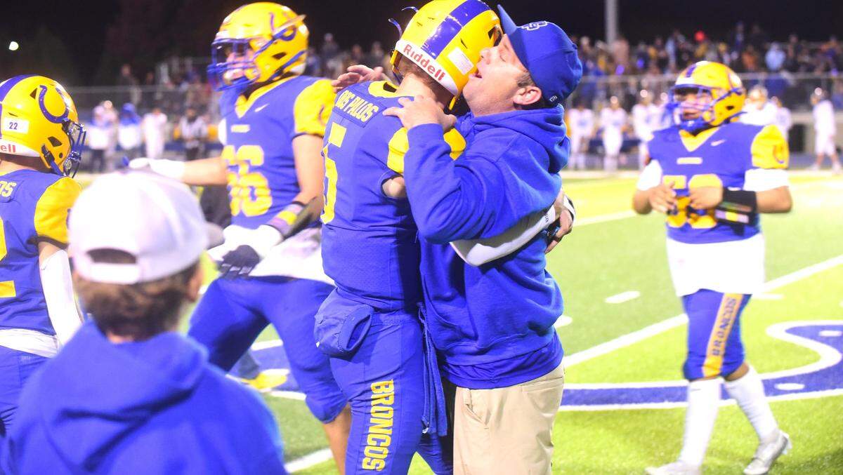 Dos Palos High School senior quarterback Peyton Van Worth (5) hugs his father Mike Van Worth after the Broncos’ 28-21 victory over Exeter in the Central Section Division IV semifinals on Friday, Nov. 17, 2023.