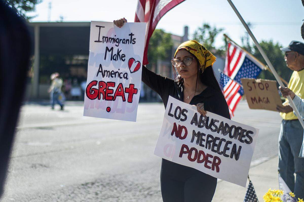 Arlhen Mejia, 19, from Peru and a student at the University of California, Merced, holds up signs while taking part in a “No Kings” protest in Merced, Calif., on Saturday, Oct. 18, 2025.