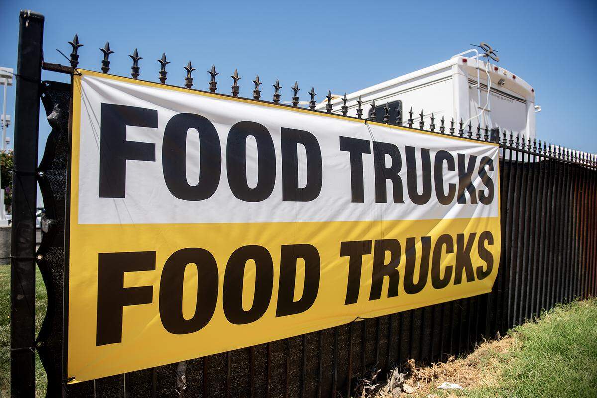 A sign hangs on a fence near a food truck parking area in the lot of Courtesy Rent a Car, 1055 W. 15th Street in Merced, Calif., on Tuesday, Aug. 12, 2025. The location currently hosts up to nine food trucks offering various cuisine options. 