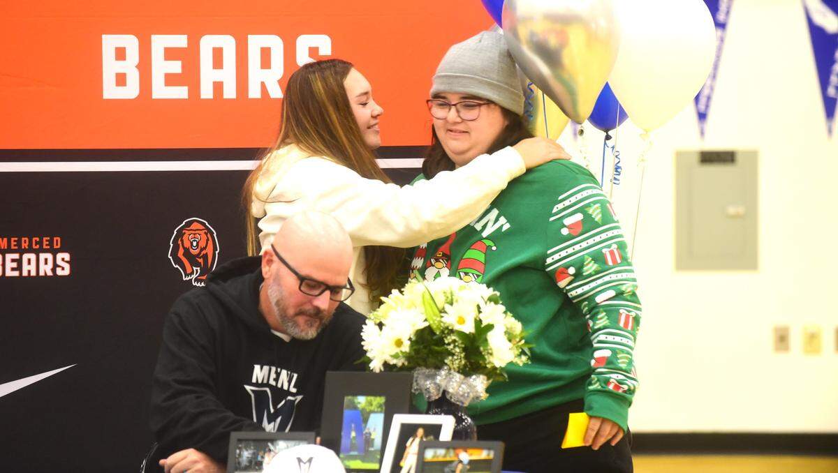 Merced High School senior Aleatha Buchner (left) hugged by Bears softball coach Jennifer Moreno after Buchner signed her national letter of intent to accept a softball scholarship to Menlo College on Wednesday, Dec. 13, 2023.