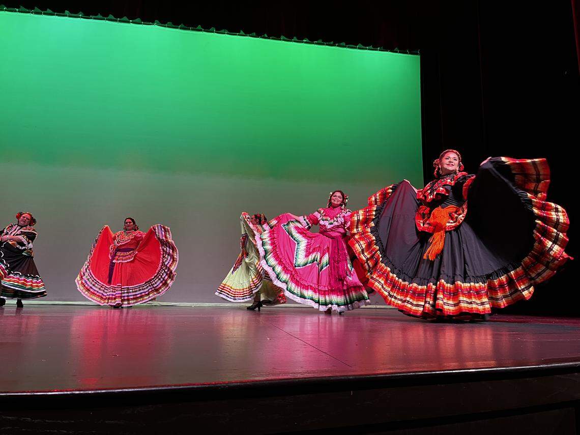 Dancers in traditional, colorful skirts dance onstage.