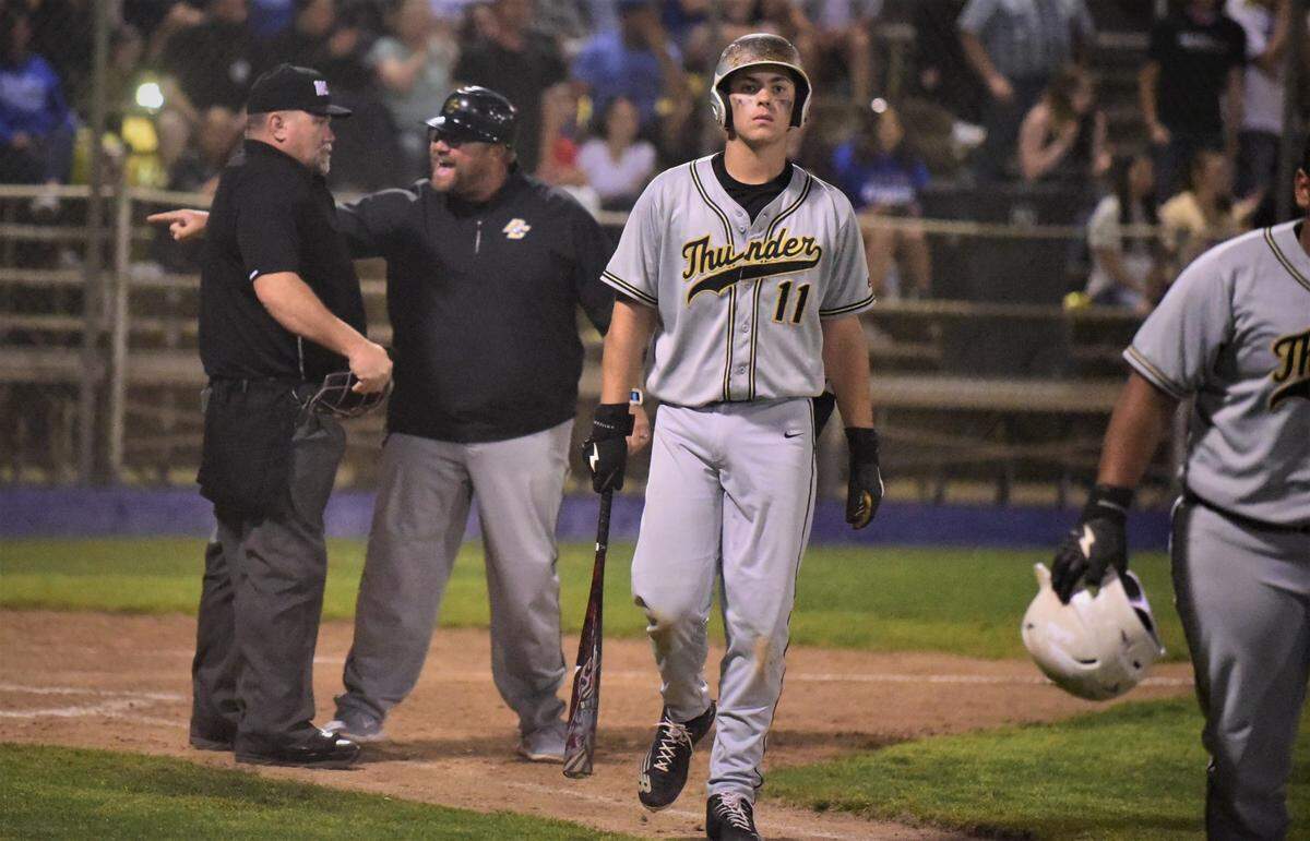 Buhach Colony junior Spencer Lanz (11) walks back to the dugout as Thunder coach Joe Medeiros argues with the home plate umpire after Buhach Colony’s Ramiro Jimenez was called out trying to score on a wild pitch during the fifth inning of a game on Friday, March 26, 2022 at Memorial Ballpark in Atwater, Calif.