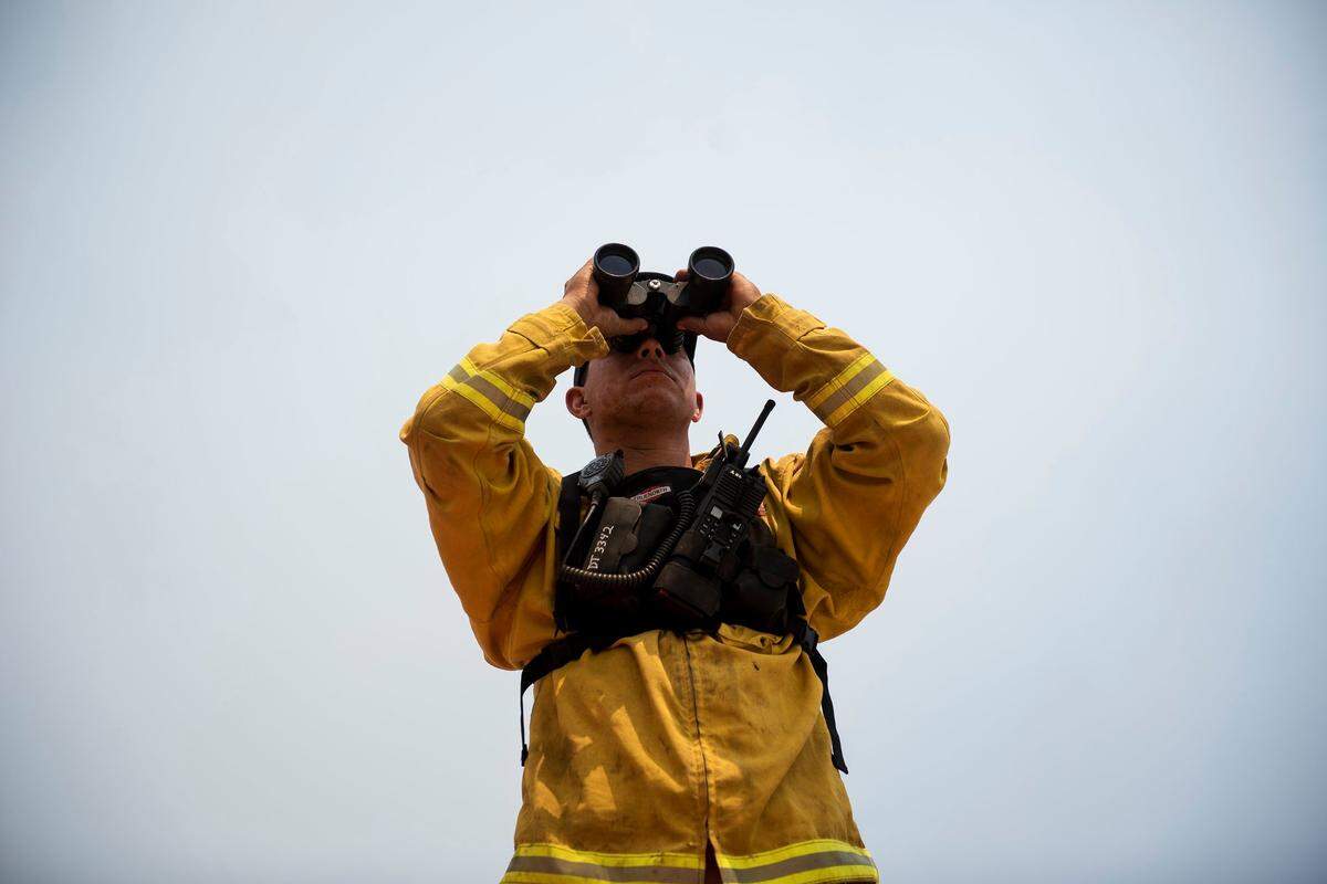A firefighter watches flames move down the hillside near the Idle Wheels mobile home park as fire crews continue to battle the Detwiler fire in Mariposa, Calif., on Wednesday, July 19, 2017.