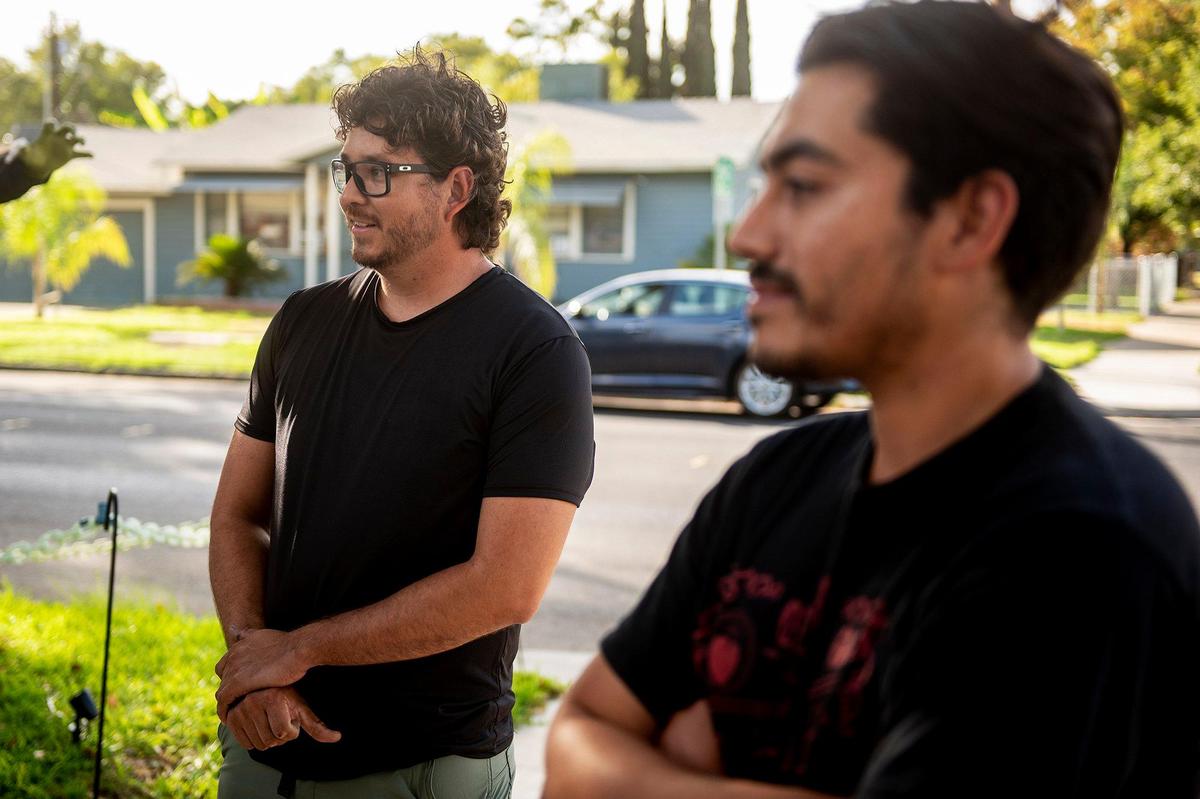 Miguel Avila, 28, left, and friend Leovardo Gallegos, 29, right, speak about the elaborate display of Halloween decorations while looking at the yard of Avila’s home on West 9th Street in Merced, Calif., on Thursday, Oct. 17, 2024.
