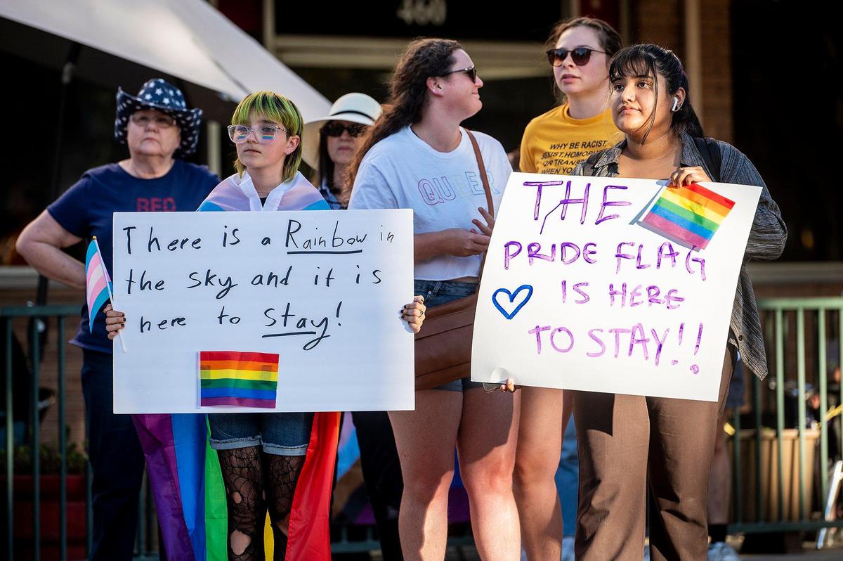 Alex Carlson, 11, of Merced, left, and Rosy Oliveros, 21, of Oakland, right, hold signs in support of the Pride flag during the Pride Progress flag raising ceremony at Bob Hart Square in Merced, Calif., on Wednesday, June 1, 2022. A person at the event had a sign stating they are against Merced City council flying the Pride flag on city property. The Merced City Council approved the addition of the pride flag to the regular flag calendar, meaning the flag will fly over Bob Hart Square annually during the month of June.