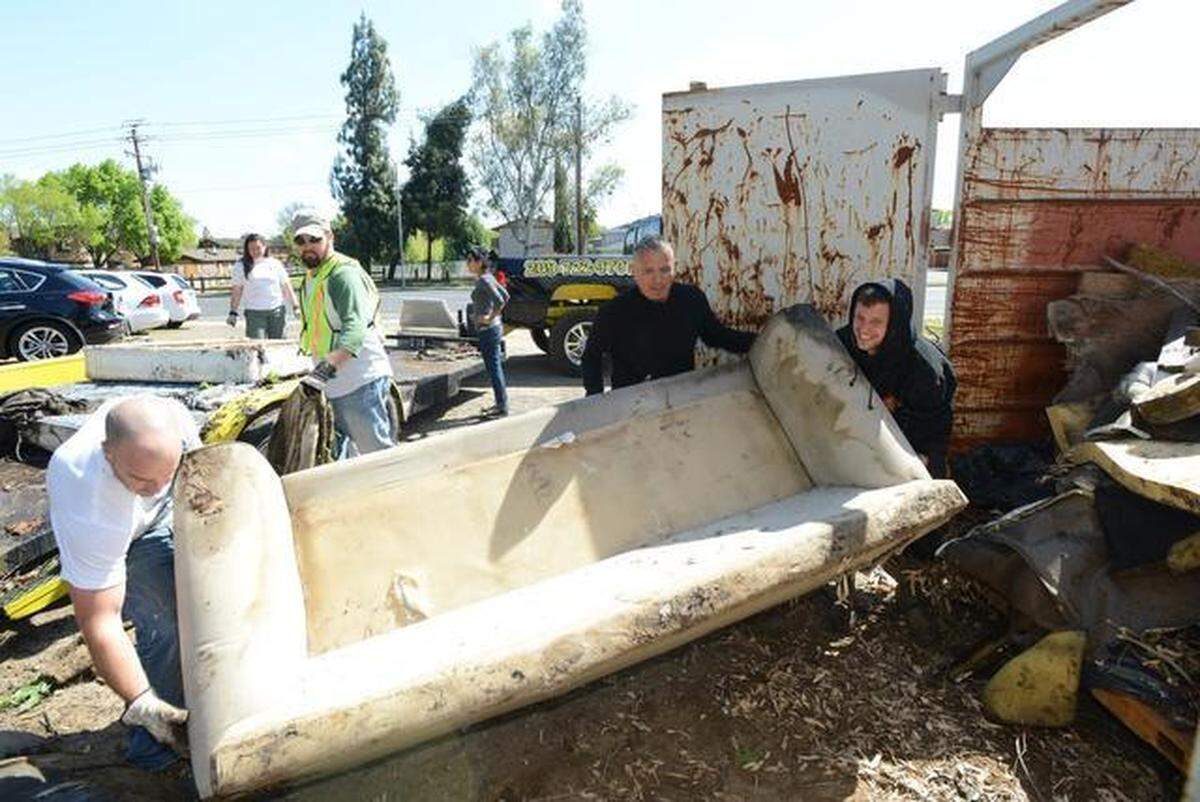 From left, Matt Raymer, Louie Gonzales and Brian Piper, all of Merced, work to get a couch that was taken pulled from the creek at Fahrens Park into a dumpster during Love Merced on April 5, 2014.