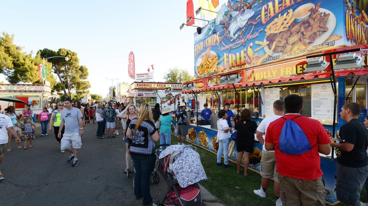 CHRISTOPHER WINTERFELDT/cwinterfeldt@mercedsunstar.com Fair goers enjoy fried treats at the midway food booths at the Merced County Fair on Thursday (6-13-13).