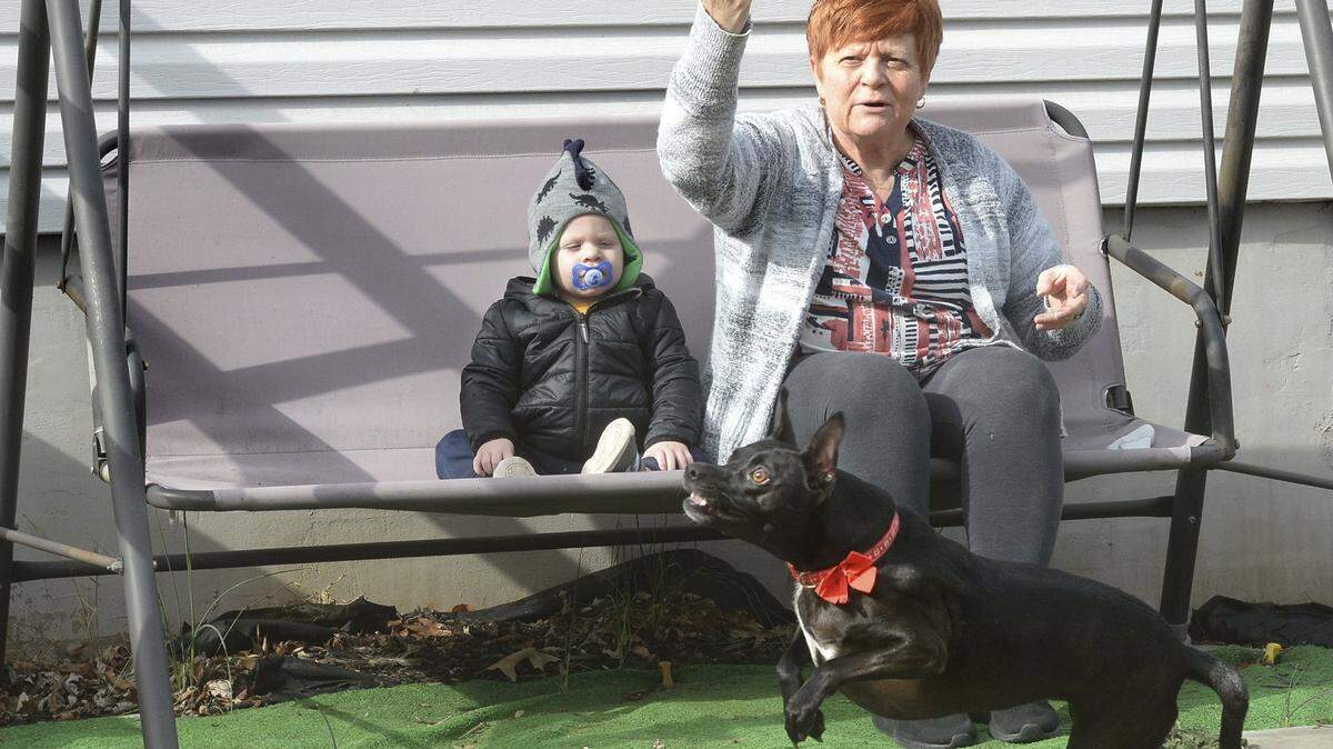 Suzanne Sigmon tosses a frisbee to her dog McKenna as she enjoys the sunshine Thursday, Feb. 20, 2020, with her great nephew Trip Jobst, 1, in front of her house on 9th Avenue in South Charleston, W. Va. (Chris Dorst/Charleston Gazette-Mail via AP)