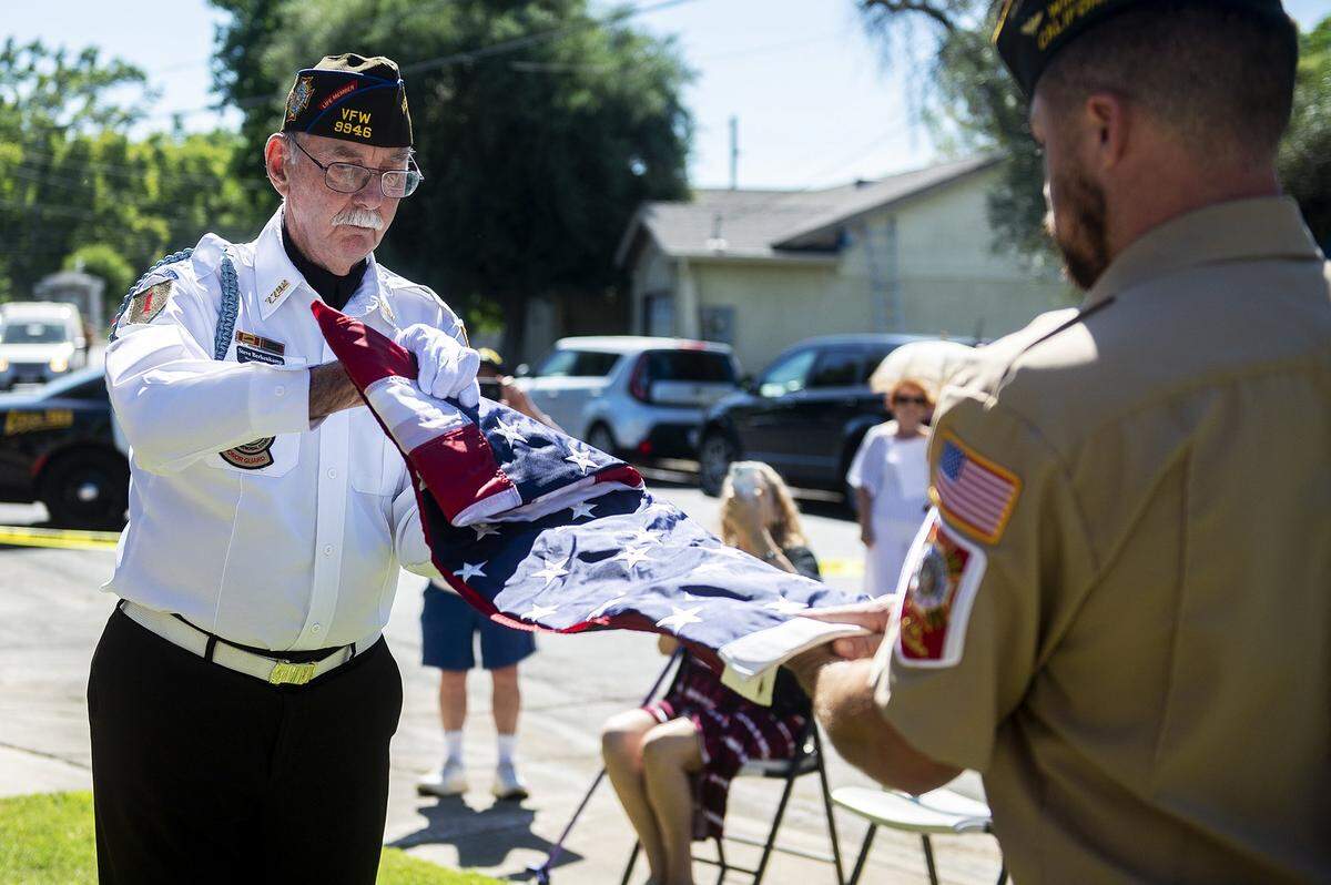 Members of the Winton VFW, Steve Berkenkamp, left, and Adam Conour, right, unfurl an American flag during a ceremony inside the Castlewood community in Atwater, Calif., on Tuesday, June 14, 2022.