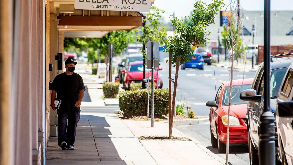 A pedestrian walks along Broadway Avenue in downtown Atwater, Calif., on Monday May 24, 2021.