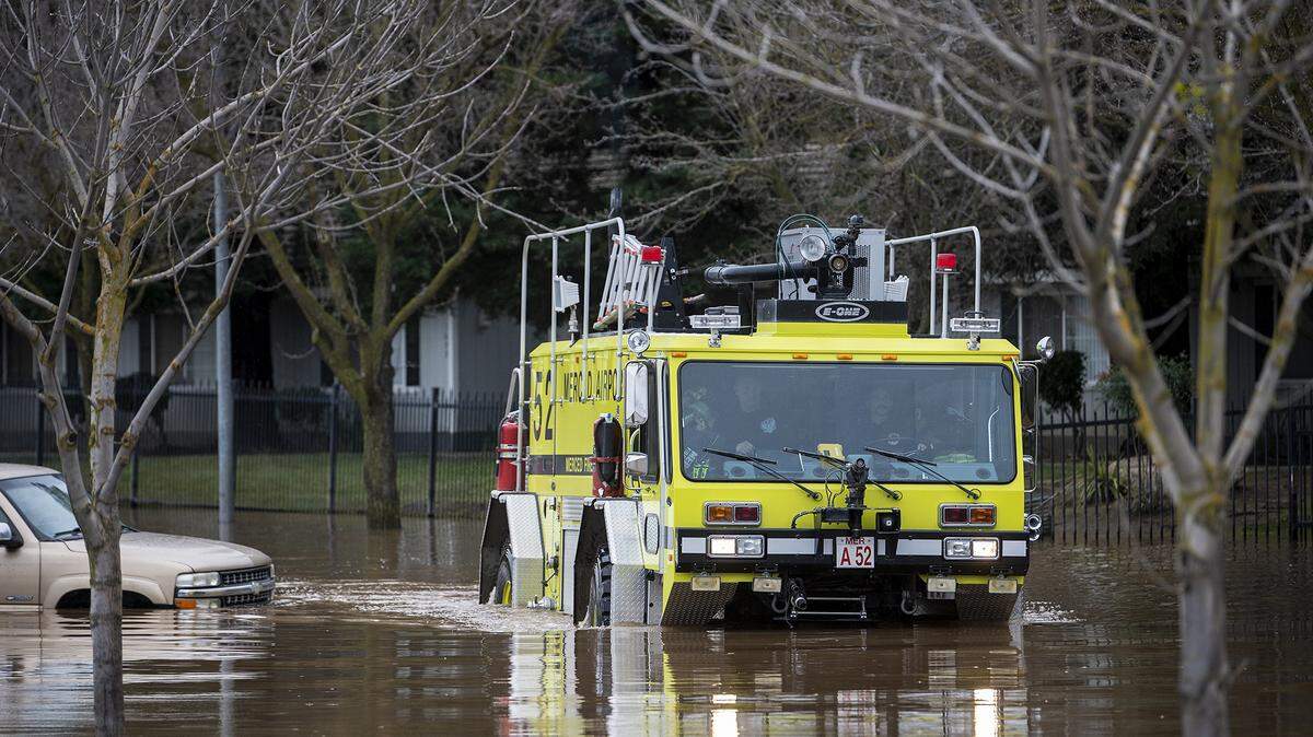 A Merced airport vehicle navigates floodwater along Willowbrook Drive near Carol Gabriault park in Merced, Calif., on Wednesday, Jan. 11, 2023.