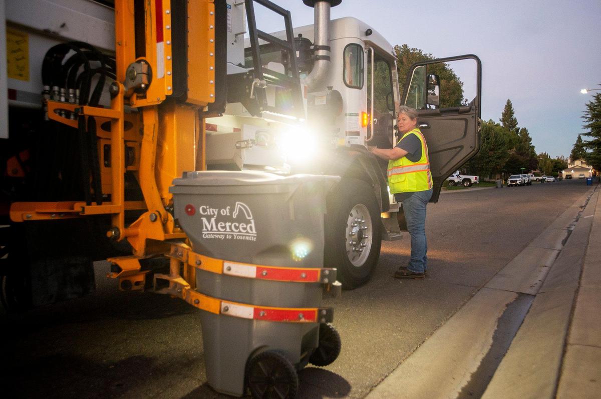 City of Merced Refuse Equipment Operator Kristie Light, 56, empties the trash bin from a home where the resident was not physically capable of moving the bin to the curb in Merced Calif. on Thursday, Oct. 24, 2024. According to Light who previously drove commercial trucks across parts of the country and would routinely be gone for 70-80 hours a week, her current job with the city allows her to spend more time at home. “It’s nice to go to work and like your job,” said Light.