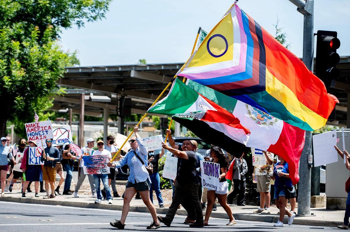 Protesters hold signs and wave flags along M Street as they take part in a “No Kings” protest in Merced, Calif., on Saturday, June 14, 2025.