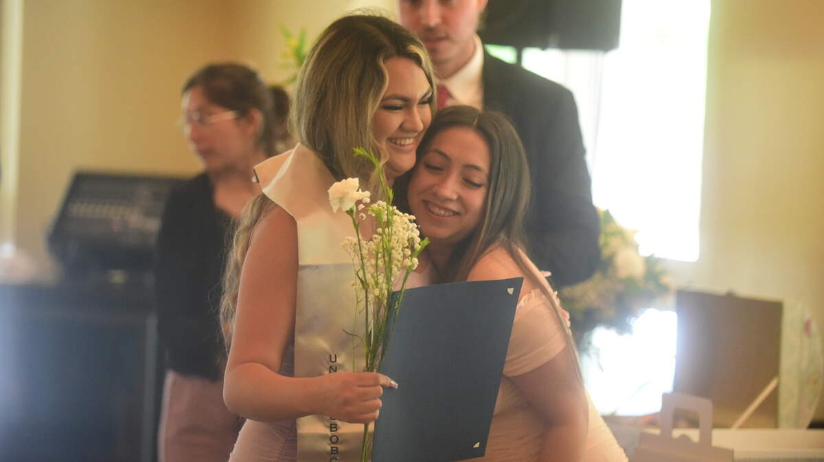 Las estudiantes de UC Merced Berenice Arango, a la izquierda, y Elizabeth Meza Torres se abrazan durante una celebración de graduación para estudiantes indocumentados el viernes 13 de mayo de 2022 en UC Merced en Merced, California.
