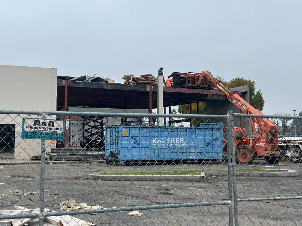 Construction workers wearing hard hats tear apart the former Sears building at 1011 W. Olive Ave. and clear the rubble on Thursday Dec. 19.