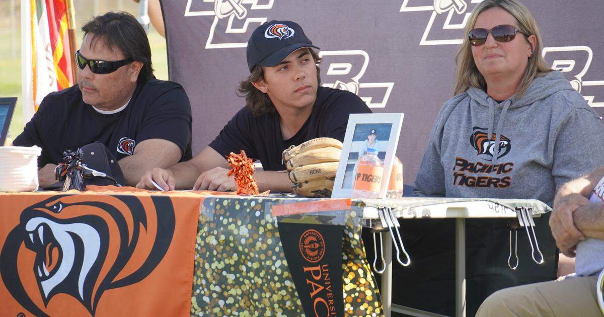 Buhach Colony High School senior Cooper Lanz signs his national letter of intent to accept a baseball scholarship to the University of the Pacific as his parents Robert and Gena Lanz look on during a ceremony on the Buhach Colony baseball field on Monday, May, 2, 2022.