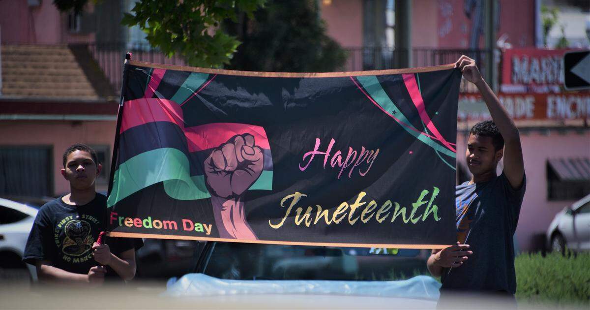 Aayden Ashford, left, and Sean Ashford hold up a Juneteenth banner on Saturday, June 17, 2023, in Merced, Calif.