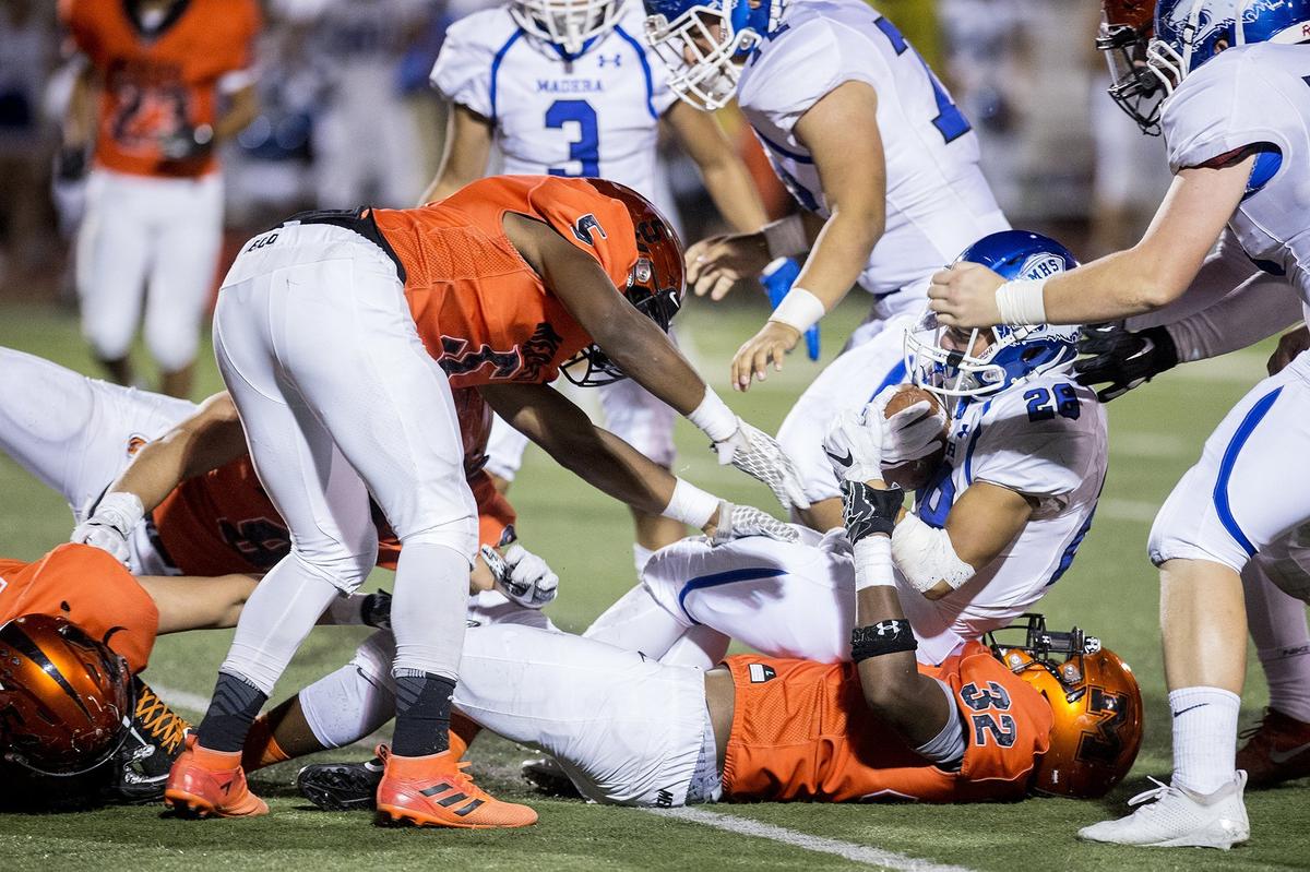 Madera sophomore Jeremiah Sanchez (28) is stopped by the Merced defense during a game at Veterans Stadium on the campus of Golden Valley High School in Merced, Calif., on Friday, Sept. 7, 2018. The Bears beat the Coyotes 63-35.