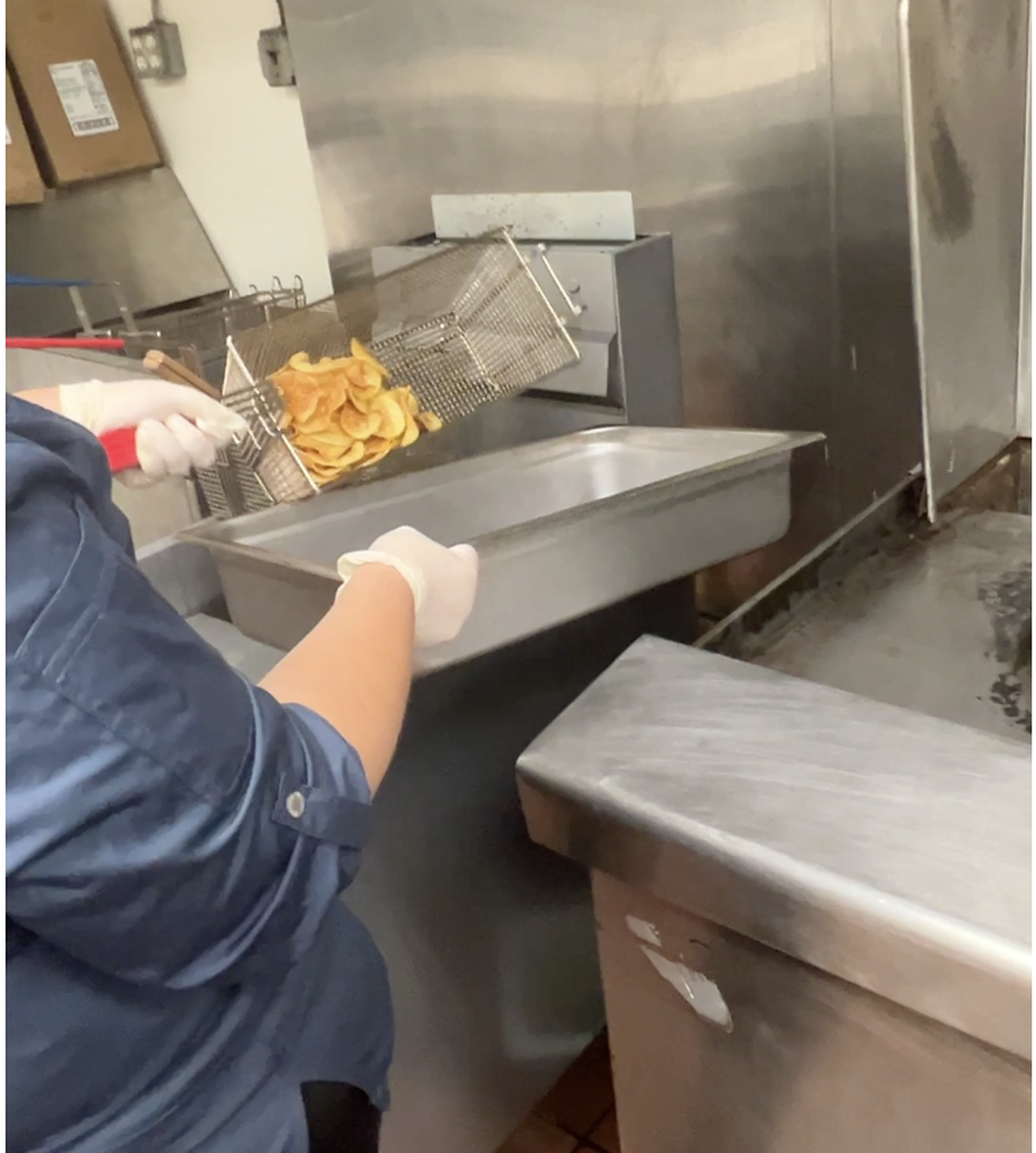 A basket of chips is lifted from a deep fryer.