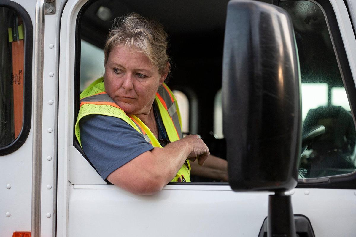 Merced Refuse Equipment Operator Kristie Light, 56, watches as picks up a refuse bin with a robotic arm on the side of the truck while collecting refuse in Merced Calif. on Thursday, Oct. 24, 2024. According to Light who previously drove commercial trucks across parts of the country and would routinely be gone for 70-80 hours a week, her current job with the city allows her to spend more time at home. “It’s nice to go to work and like your job,” said Light.