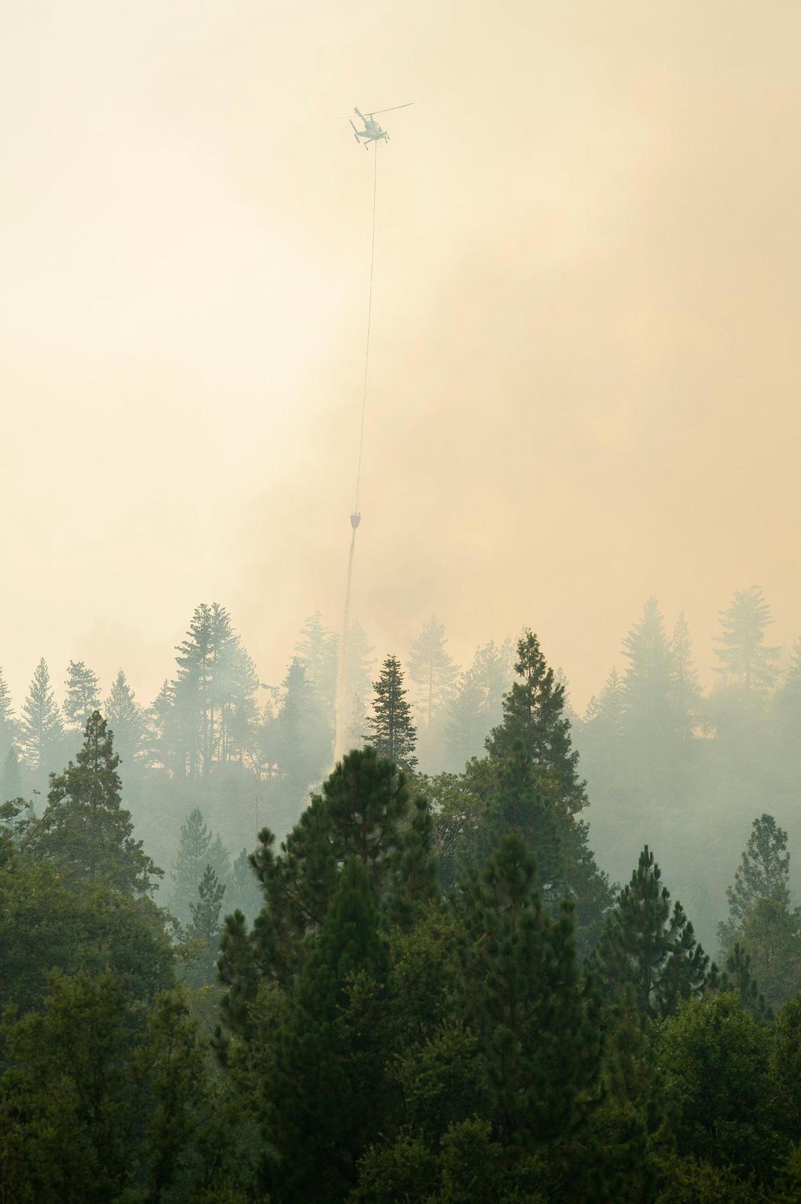 A helicopter drops water west of Scott Road as firefighters continue to battle the Oak Fire in Mariposa County, Calif., on Tuesday, July 26, 2022.