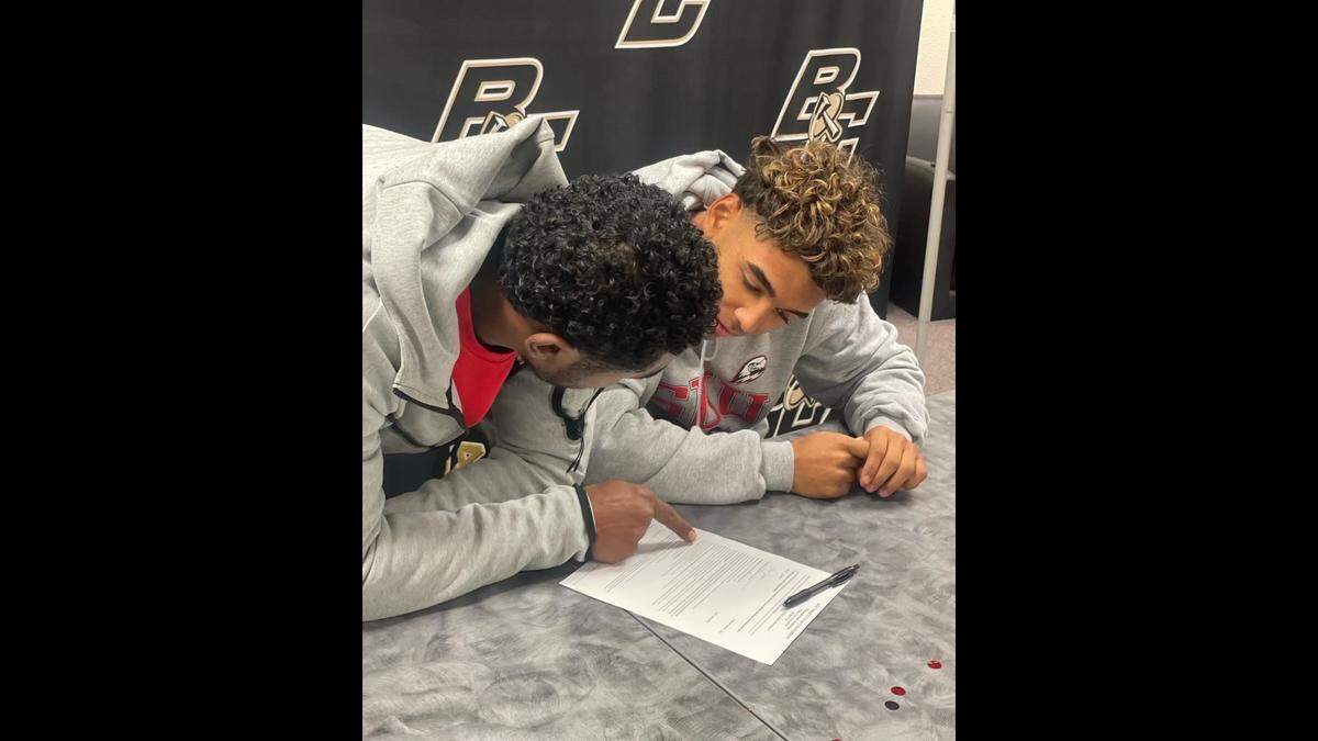 Buhach Colony High School senior Jaxson Percoats (right) and his father Imani Percoats look over his national letter of intent during Percoats’ signing ceremony at Buhach Colony on Wednesday, Dec. 21, 2022.