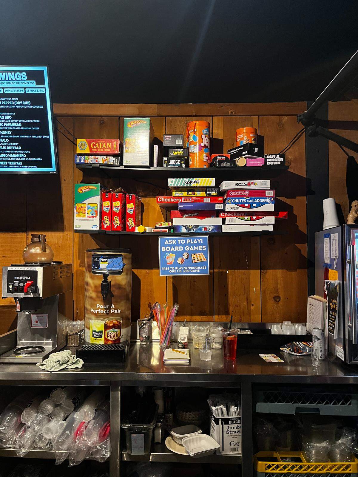 A pile of boardgames behind the counter where food is served.