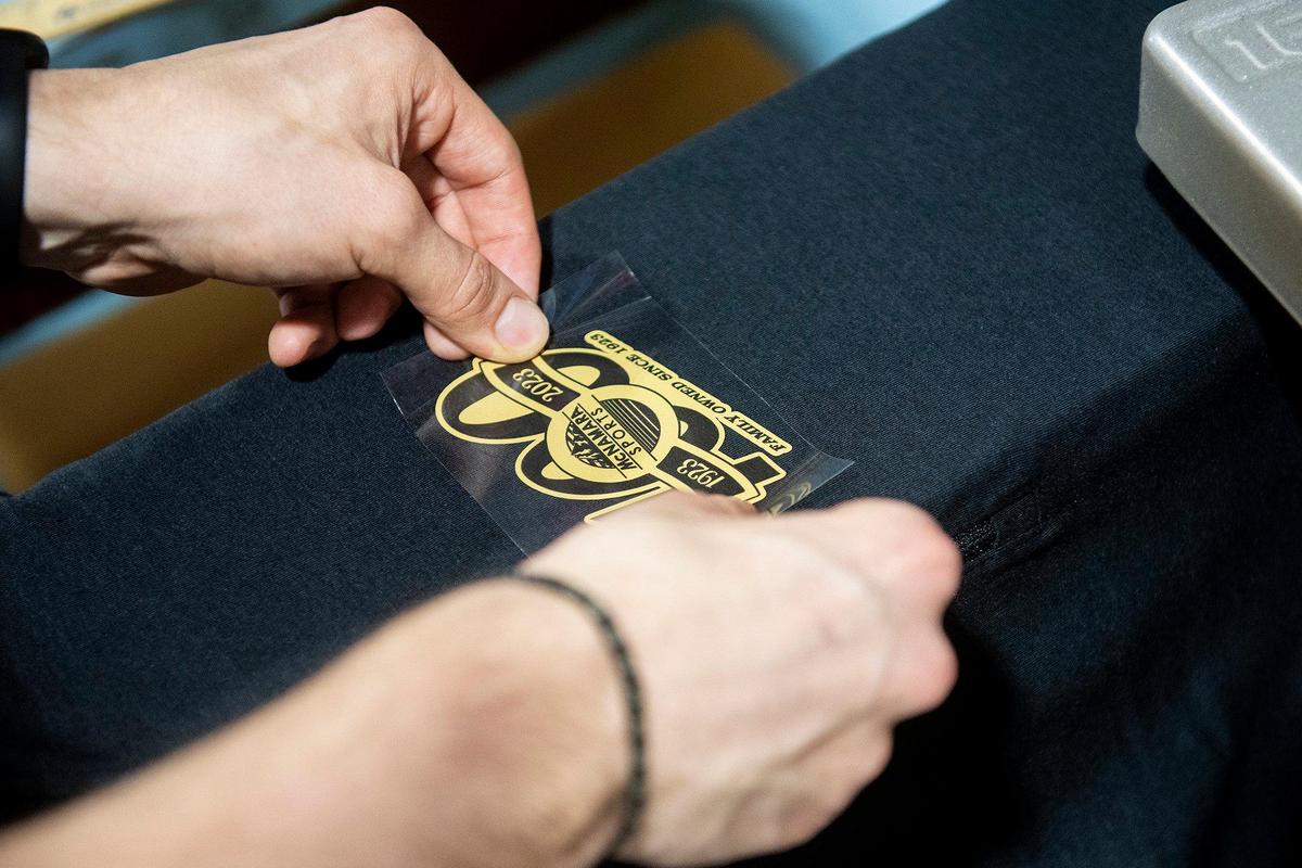 Jackson Kane, 20, of Merced, adds a logo to shirts at McNamara Sports, located at 437 W. 18th Street in Merced, Calif., on Monday, May 8, 2023. The family owned store which sells athletic equipment, team uniforms, business apparel and offers screen printing and embroidery services, is celebrating 100 years in business