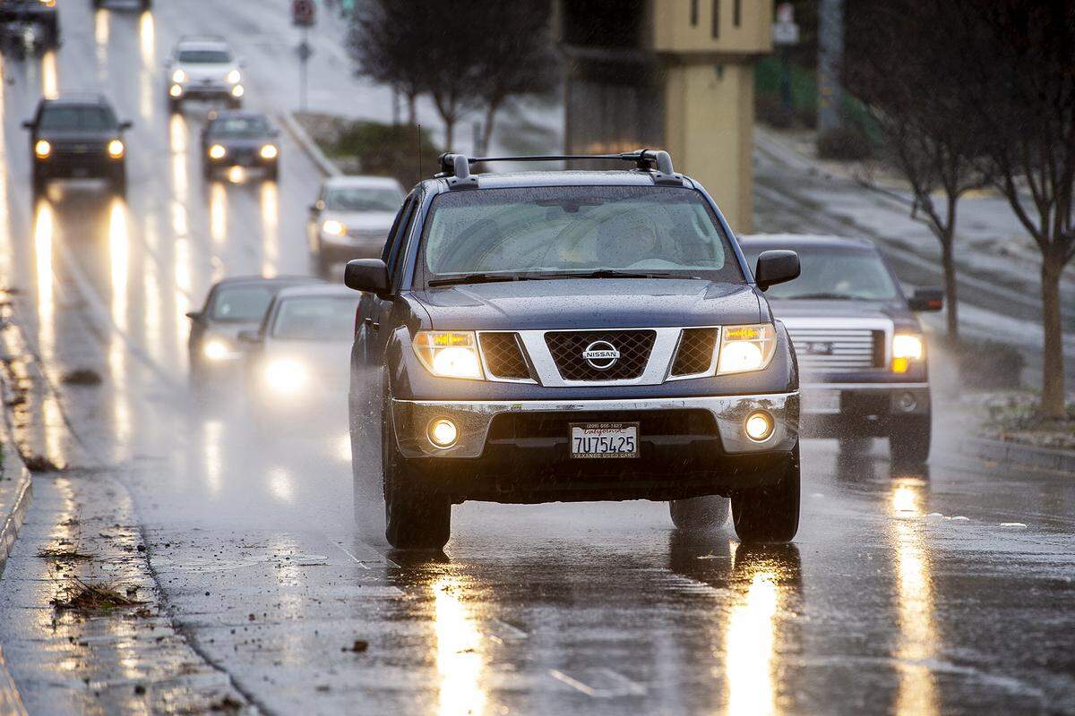 Motorists drive along G Street as rain showers move through Merced, Calif., on Wednesday, Jan. 27, 2021.