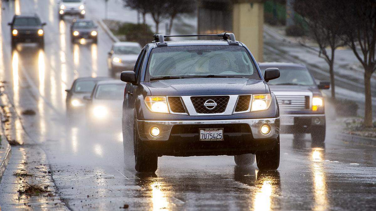 Motorists drive along G Street as rain showers move through Merced, Calif., on Wednesday, Jan. 27, 2021.