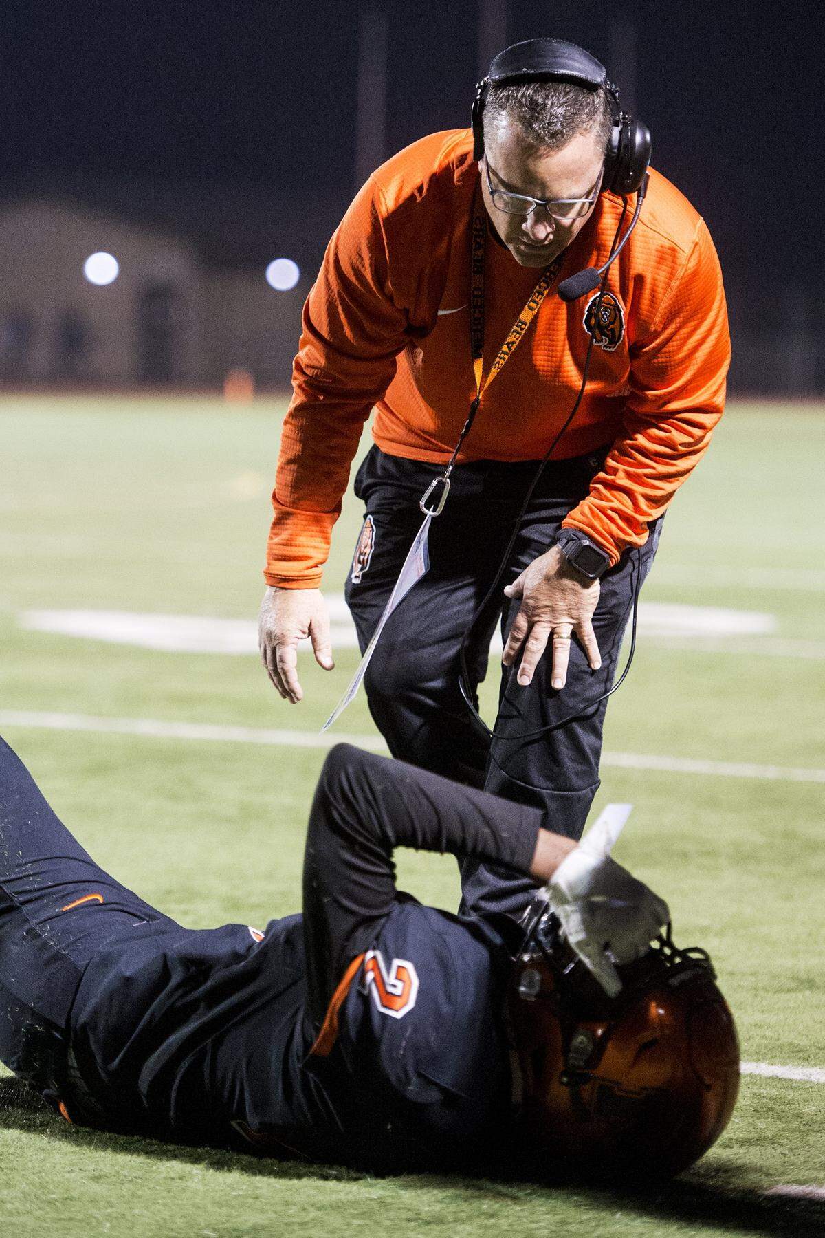 Merced head coach Rob Scheidt checks on injured player Xavier Stewart (2) during a CIF Sac-Joaquin Section Division III playoff game against River Valley at Veterans Stadium in Merced, Calif., on Friday, Nov. 9, 2018. The Falcons beat the Bears 45-40.