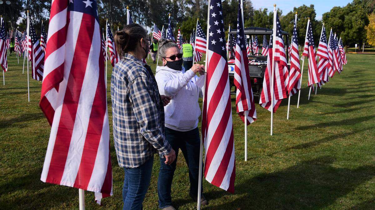 Volunteers Diatte Cartwright (left) and Lisa Zucconi help tag flags with the name of veterans at the Field of Honor on the front lawn of Merced College in Merced, Calif. on Saturday, Nov. 7, 2020.