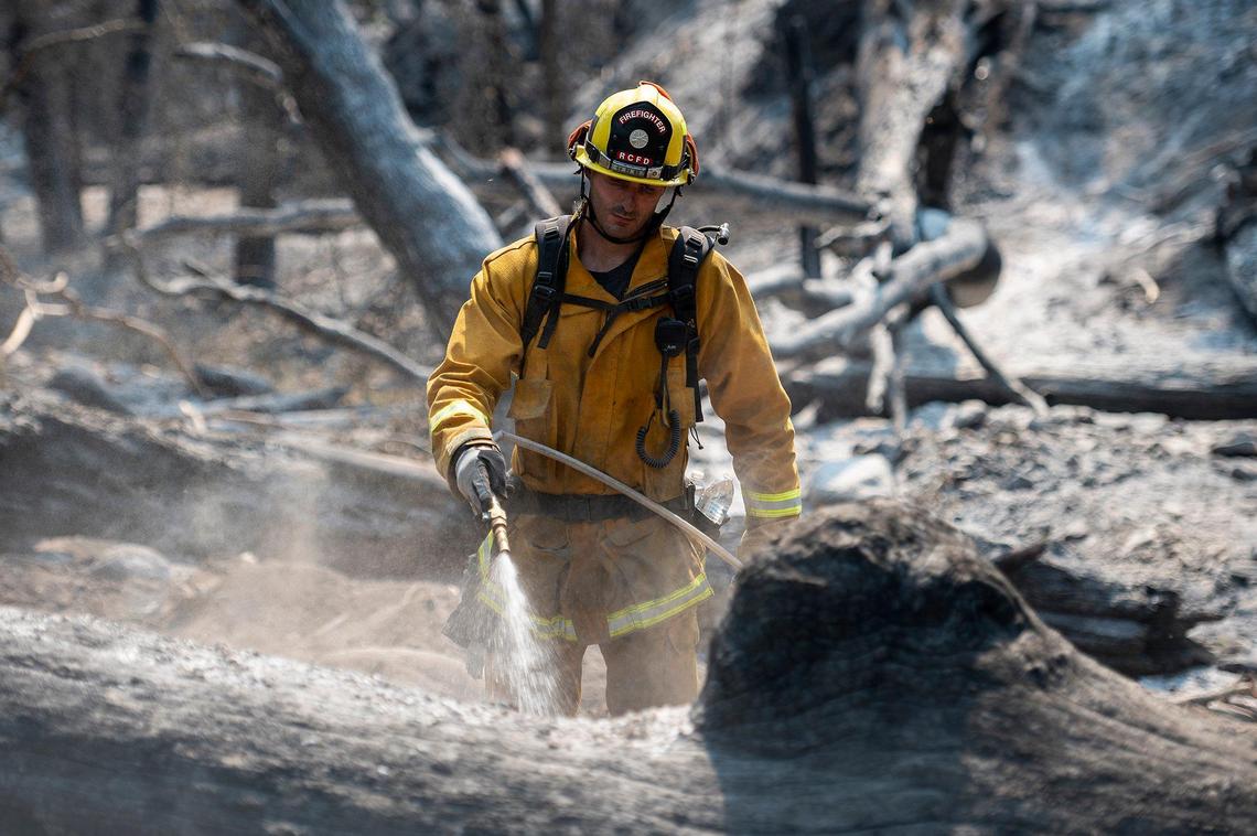 Firefighters extinguish hot spots near the intersection of Jerseydale and Triangle roads as firefighters continue to battle the Oak Fire in Mariposa County, Calif., on Tuesday, July 26, 2022.