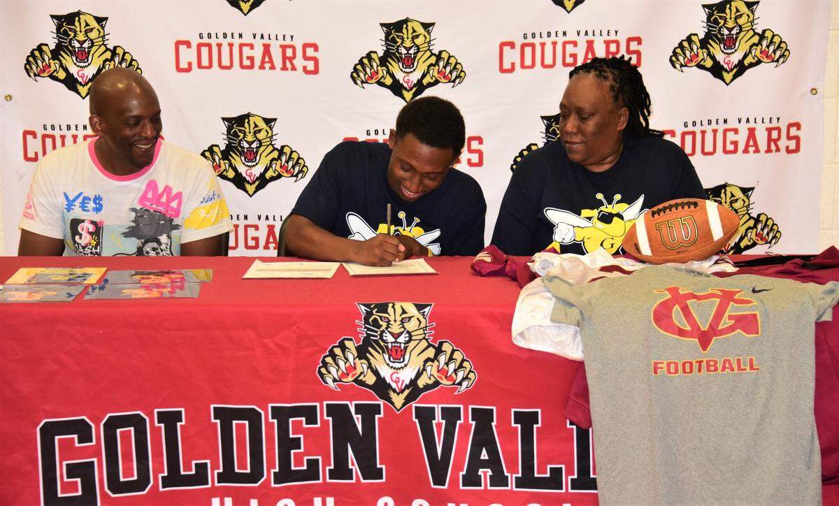Golden Valley High School senior Jahkylle Smith signs his national letter of intent to accept a football scholarship to Graceland University in Iowa as his stepfather Duke Lane (left) and mother Chuckie Lane look on during a ceremony at Golden Valley High School on Thursday, May 18, 2023.