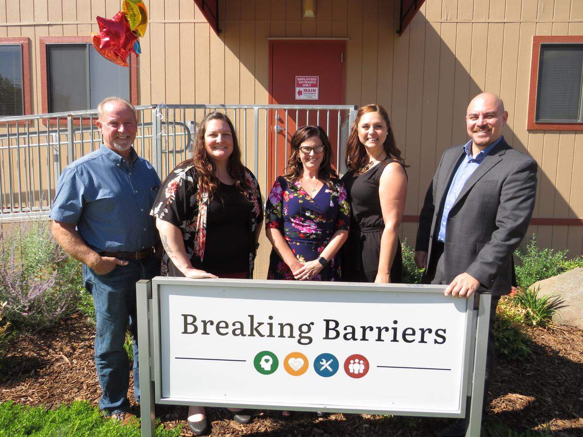 Lloyd Pereira, the District 4 Merced County supervisor, Tristin Gresham, the probation program specialist for Breaking Barriers, Kalisa Rochester, chief probation officer for Merced County Probation, Genevieve Valentine, director of Behavioral Health and Recovery Services for Merced County, and Erik Serrato, director of Workforce Investment for Merced County, left to right, smile for a group photo in front of the Breaking Barriers building in Los Banos, California.